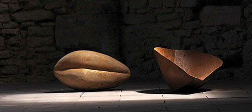 Überdimensioniertes Saatkorn mit Spreu aus Holz in Lichtkegel getaucht auf dem Boden der abgedunkelten Wintringer Kapelle